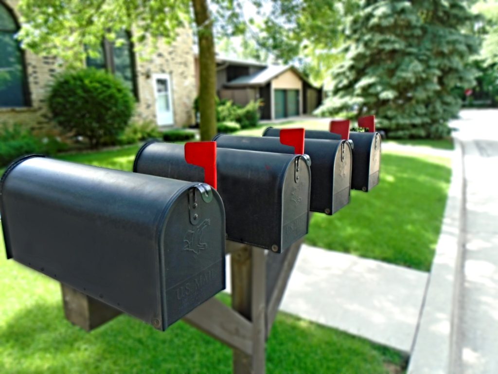Four black mailboxes in a row on a post.