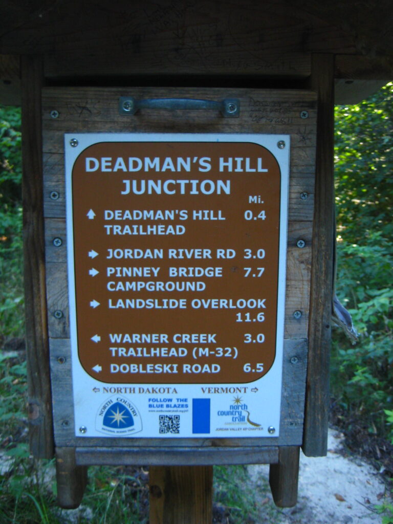 Trail marker titled "Deadman's Hill Junction," with destinations and distances if you go straight, to the left, or to the right.