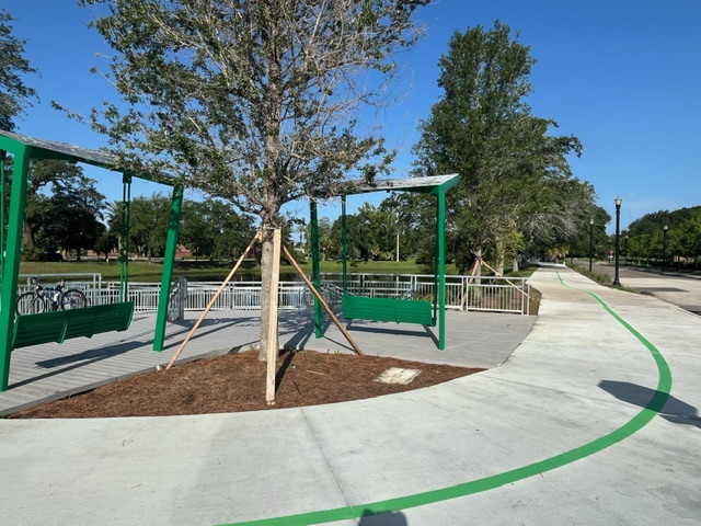 Two emerald green bench swings at LaVilla Pond Park off the LaVilla Link of the Emerald Trail in Jacksonville.